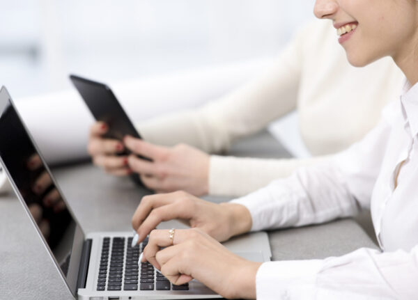 smiling-young-businesswoman-typing-laptop-desk